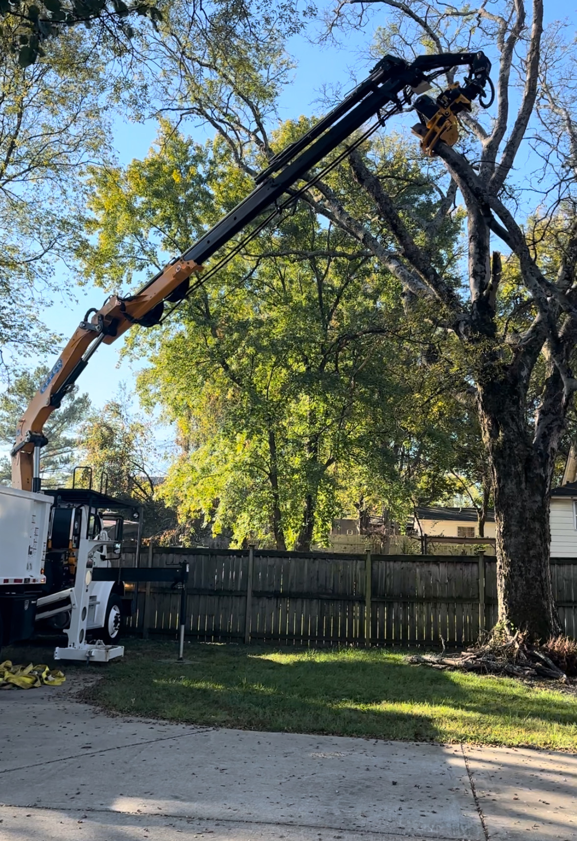 Knuckleboom grapple crane lifting a large limb during a Nashville-area removal